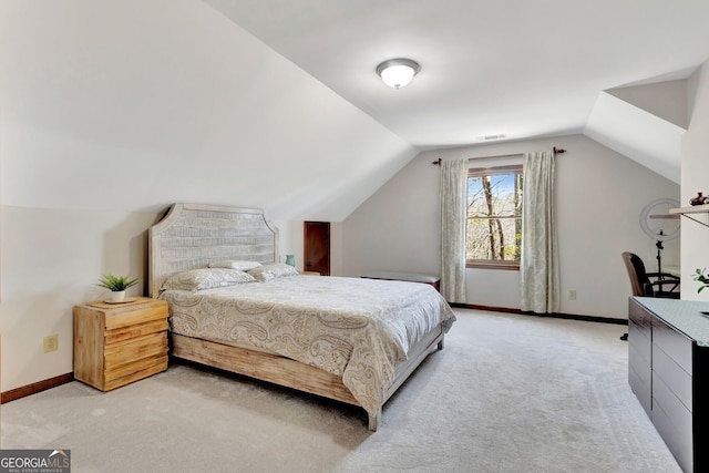 bedroom with visible vents, light colored carpet, baseboards, and vaulted ceiling