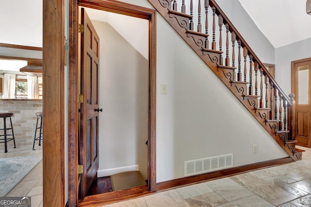 stairway featuring visible vents, baseboards, stone finish floor, and vaulted ceiling