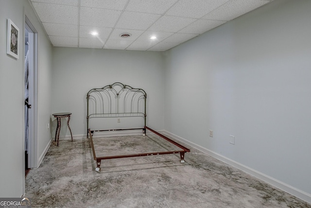 unfurnished bedroom with a paneled ceiling, visible vents, concrete flooring, and baseboards