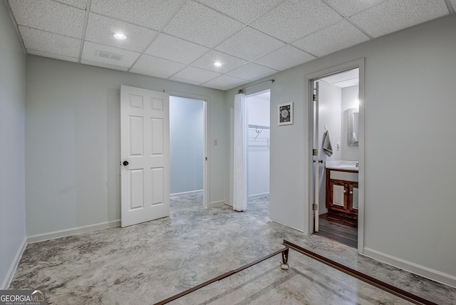 interior space with a drop ceiling, baseboards, and a walk in closet