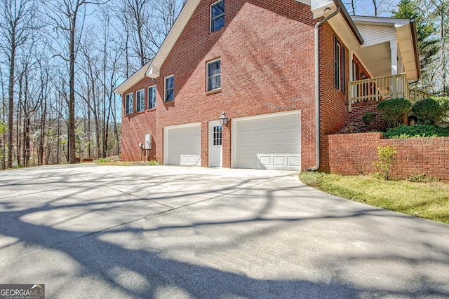 view of home's exterior featuring brick siding, an attached garage, and driveway