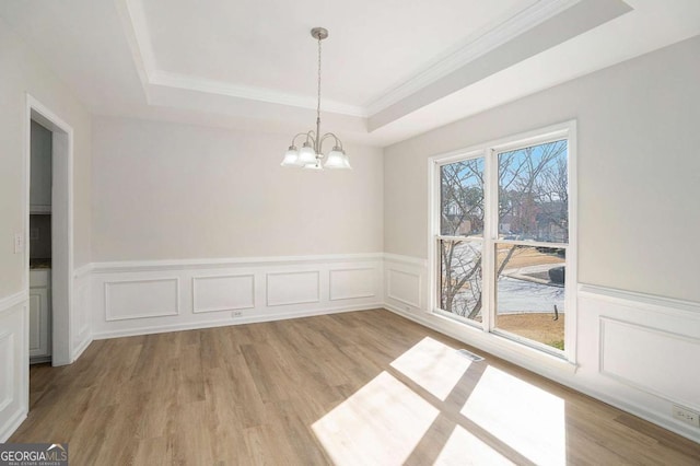 10950 Glenhurst Pass, Duluth, GA 30097 - unfurnished dining area with a tray ceiling, a chandelier, light wood-style flooring, a wainscoted wall, and crown molding