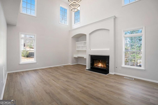 10950 Glenhurst Pass, Duluth, GA 30097 - unfurnished living room featuring a high ceiling, wood finished floors, a fireplace with flush hearth, baseboards, and built in features