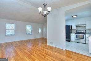 unfurnished dining area with light wood-style flooring, lofted ceiling, and a chandelier