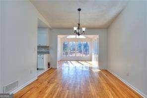 unfurnished dining area with visible vents, wood finished floors, and a chandelier