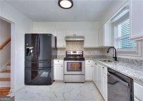 kitchen featuring black appliances, a sink, under cabinet range hood, backsplash, and white cabinets