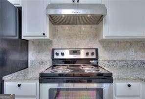 kitchen featuring under cabinet range hood, decorative backsplash, white cabinetry, and electric stove