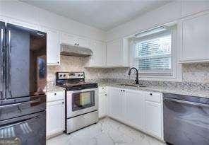 kitchen featuring ventilation hood, stainless steel appliances, decorative backsplash, white cabinetry, and marble finish floor