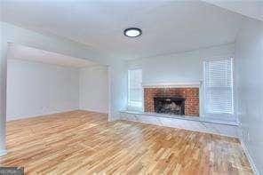 unfurnished living room with a brick fireplace and wood finished floors