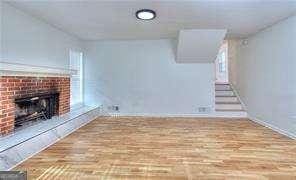 unfurnished living room featuring a fireplace, stairs, and wood finished floors