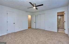 unfurnished bedroom with connected bathroom, carpet, and ceiling fan