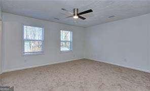 carpeted spare room featuring a ceiling fan and baseboards