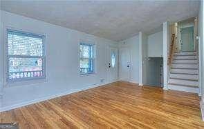 unfurnished living room featuring stairs and wood finished floors