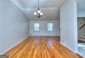 unfurnished dining area with wood finished floors, stairway, baseboards, lofted ceiling, and a chandelier