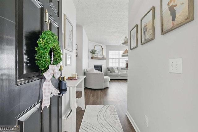 corridor with a textured ceiling, baseboards, and wood finished floors