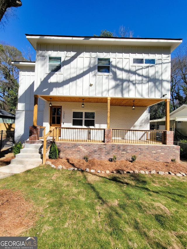 view of front of property with a porch, brick siding, board and batten siding, and a front lawn