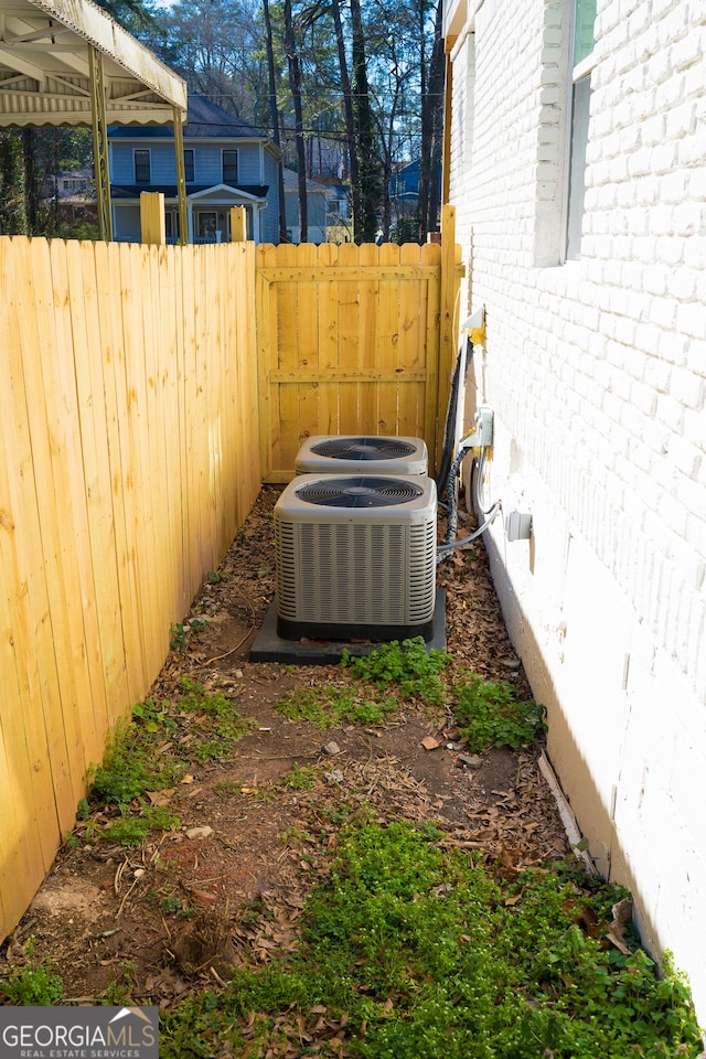 exterior details featuring brick siding, central AC, and fence