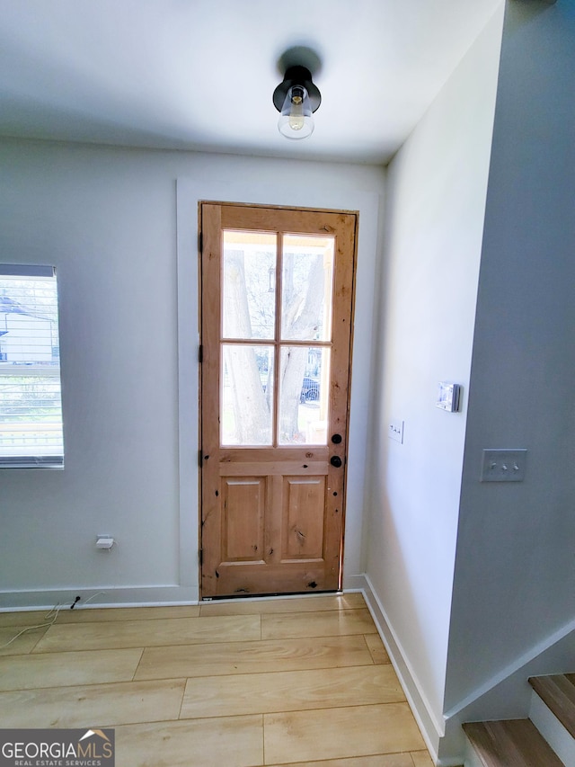 doorway to outside featuring light wood-style flooring and baseboards