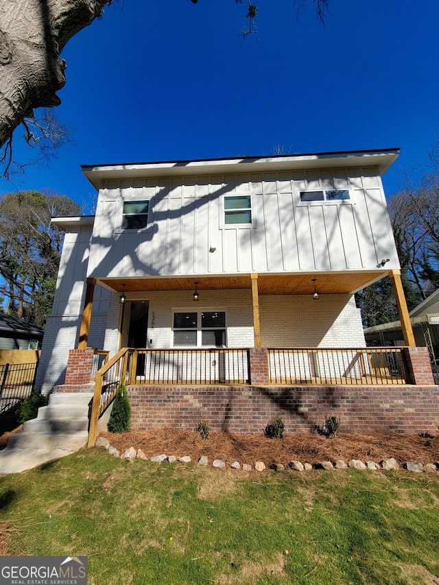 view of front of house with board and batten siding, brick siding, and covered porch