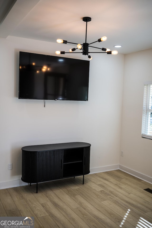 unfurnished living room with a chandelier, visible vents, baseboards, and wood finished floors