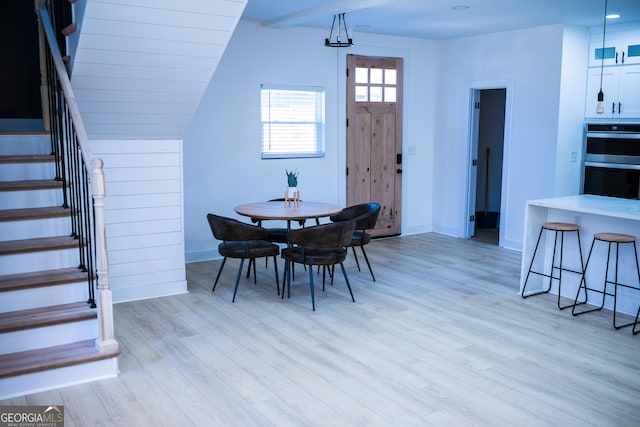 dining area featuring stairs, vaulted ceiling, baseboards, and light wood-type flooring