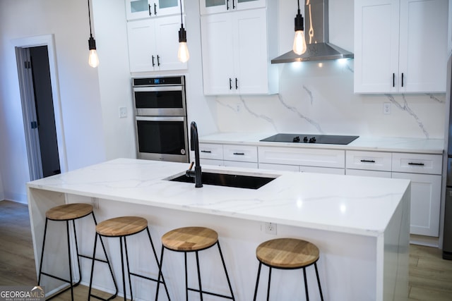 kitchen with black electric stovetop, double oven, decorative backsplash, wall chimney exhaust hood, and a sink