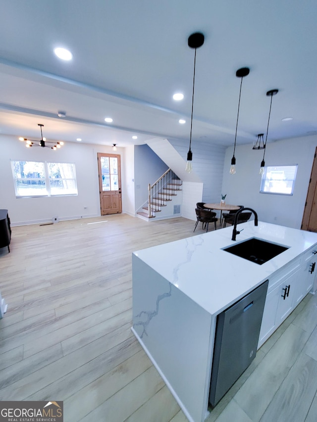 kitchen featuring a sink, light wood-type flooring, stainless steel dishwasher, and open floor plan