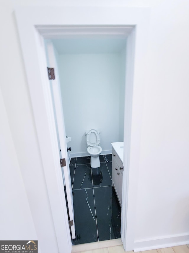 bathroom featuring vanity, toilet, and baseboards