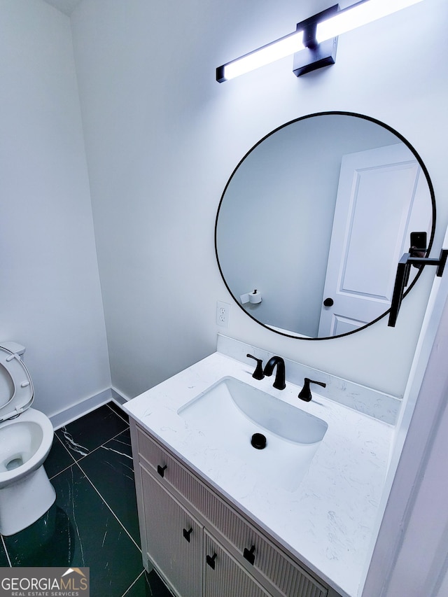 half bath featuring vanity, toilet, baseboards, and marble finish floor