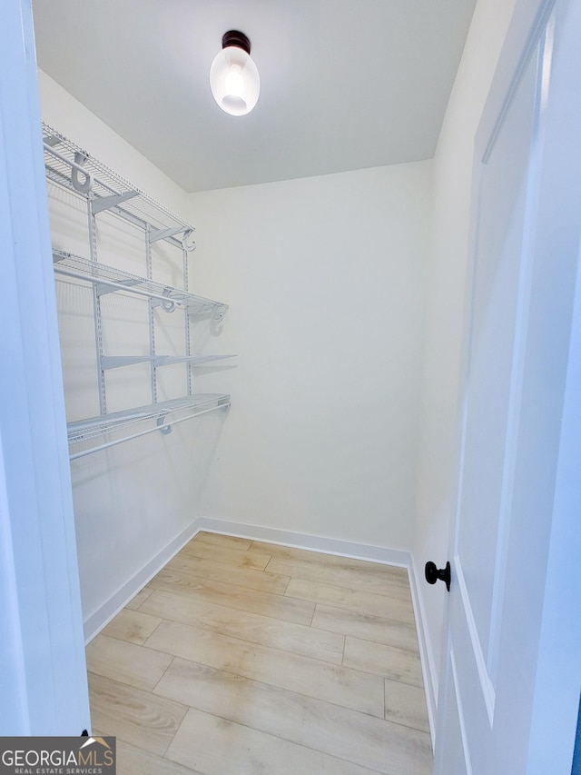 walk in closet with wood finished floors