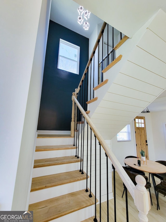 stairs featuring wood finished floors and a towering ceiling