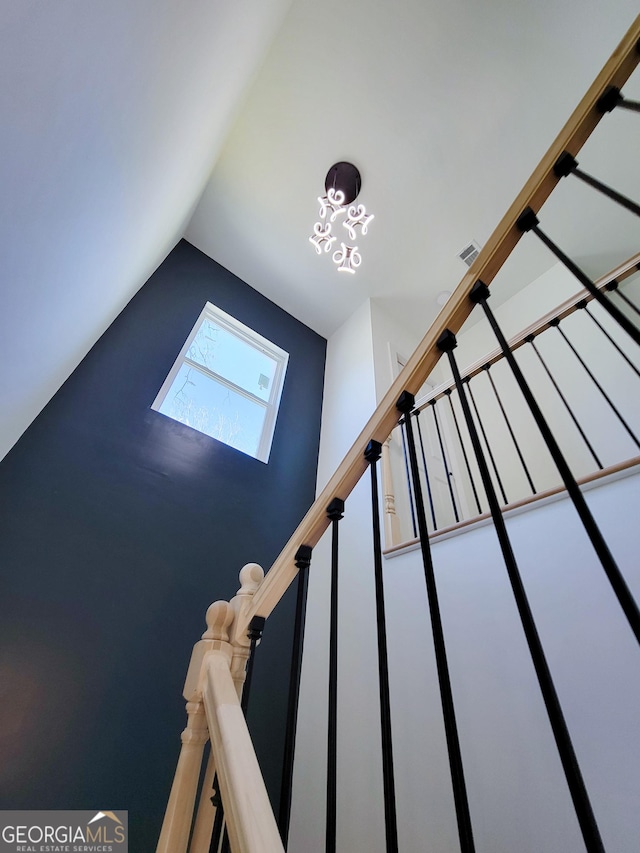 stairs with visible vents and vaulted ceiling with skylight