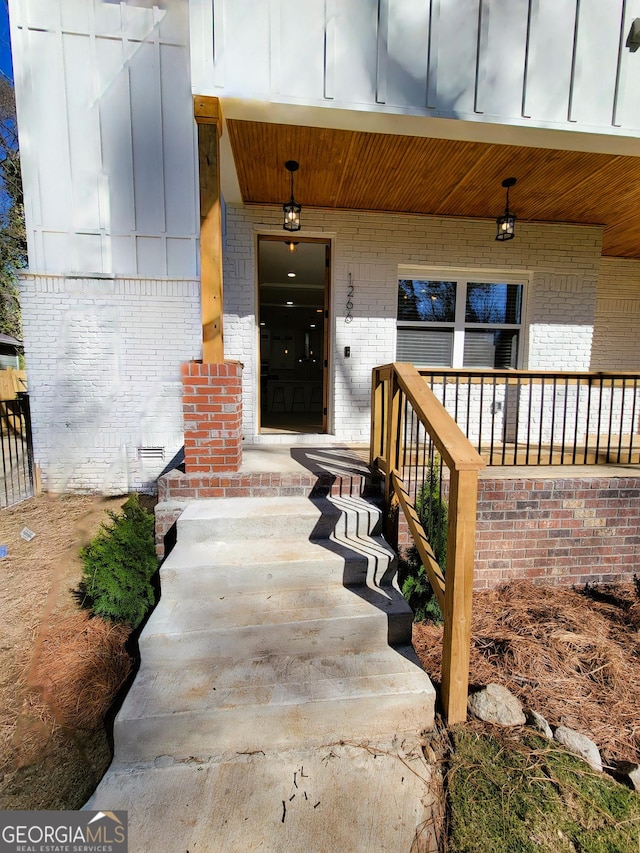 property entrance with brick siding, covered porch, and board and batten siding