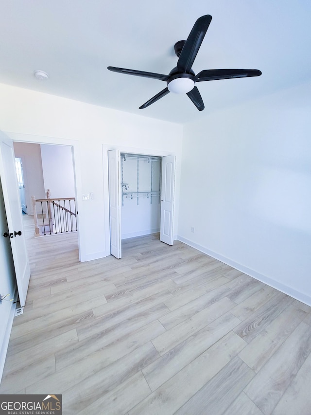 unfurnished bedroom featuring ceiling fan, a closet, baseboards, and wood finished floors