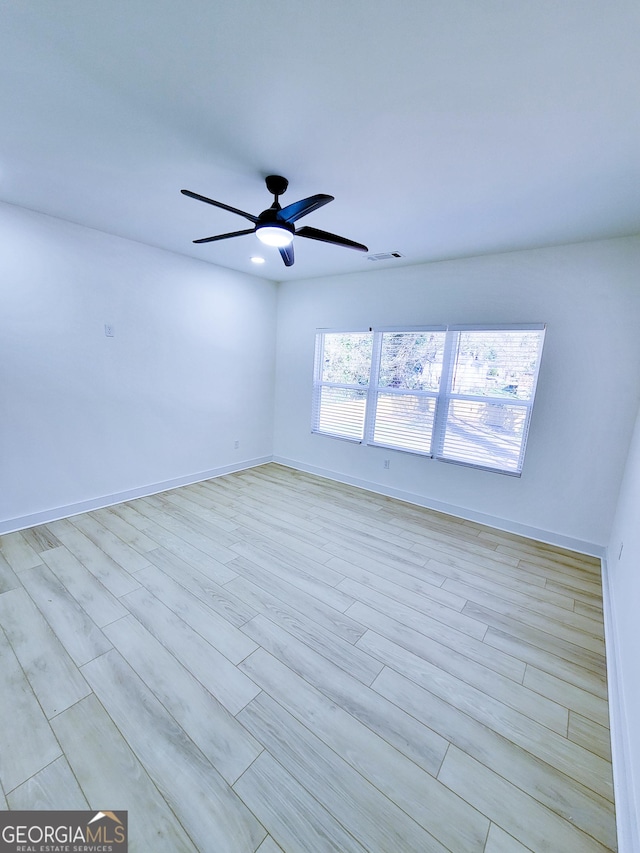 empty room with a ceiling fan, wood finished floors, baseboards, and visible vents