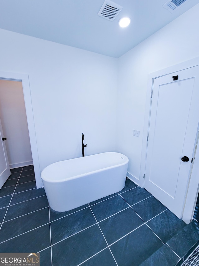 full bathroom with tile patterned floors, visible vents, baseboards, and a freestanding tub