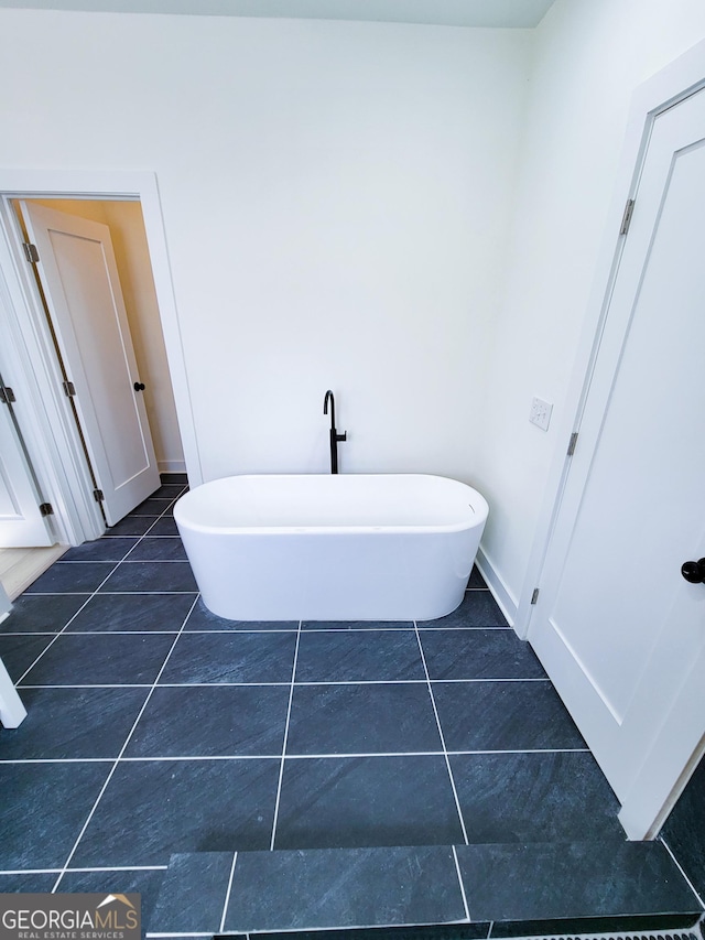 bathroom featuring tile patterned flooring, a soaking tub, and baseboards