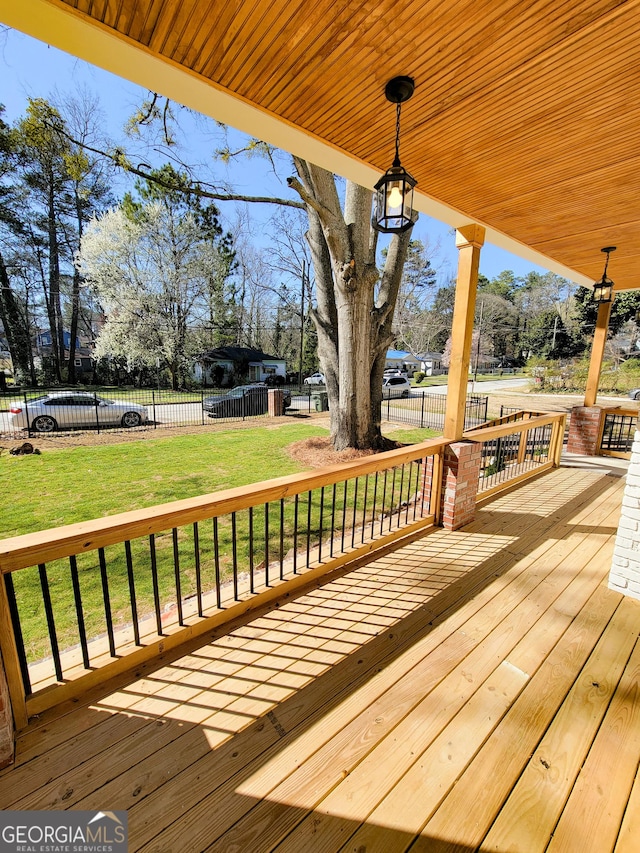 wooden terrace featuring a lawn and fence