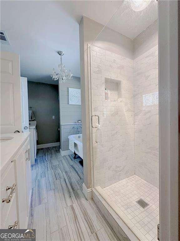 full bath with visible vents, a stall shower, vanity, and a chandelier