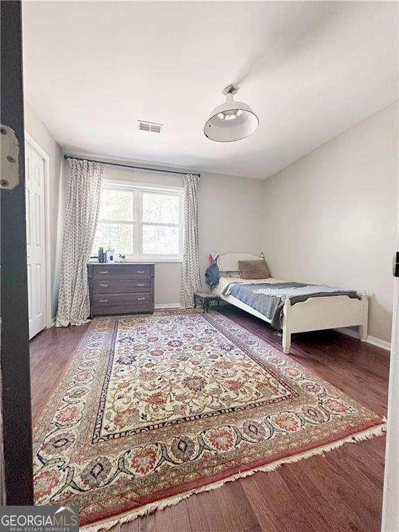 bedroom featuring visible vents, baseboards, and wood finished floors