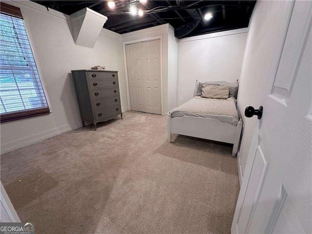 bedroom with baseboards, a closet, and light carpet