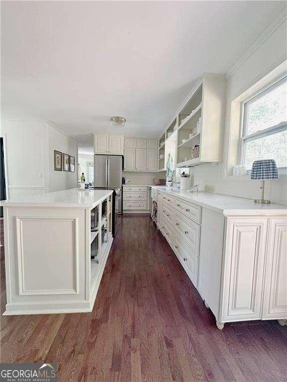 kitchen with dark wood finished floors, open shelves, a kitchen island, and stainless steel appliances