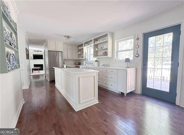 kitchen with dark wood finished floors, light countertops, freestanding refrigerator, white cabinets, and open shelves