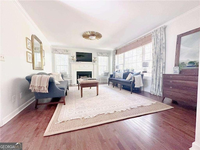 living area with a fireplace, crown molding, baseboards, and wood finished floors