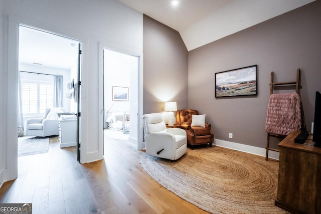 living area with baseboards, lofted ceiling, and wood finished floors