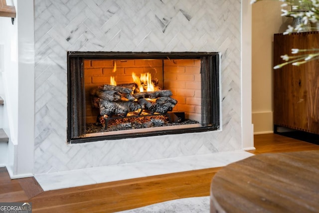 interior details with a fireplace with flush hearth, wood finished floors, and baseboards