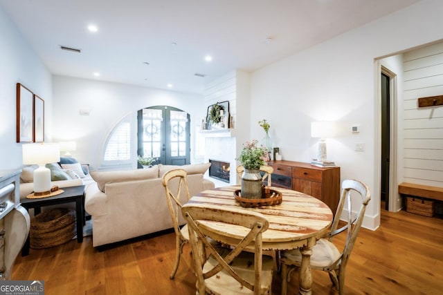 dining room with recessed lighting, a lit fireplace, and wood finished floors