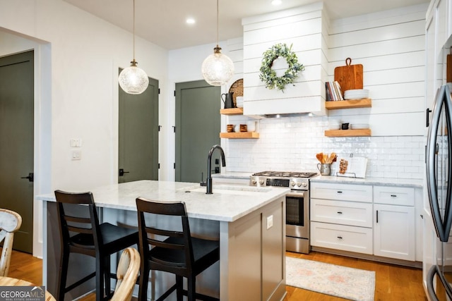 kitchen with a sink, light stone countertops, white cabinets, stainless steel appliances, and open shelves