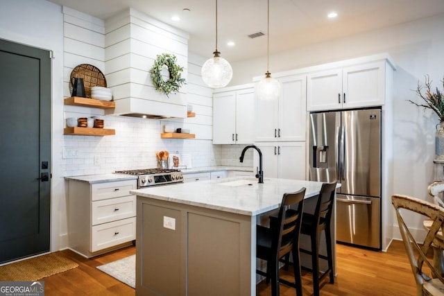 kitchen with open shelves, wood finished floors, stainless steel fridge, and a sink