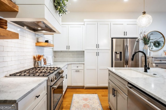 kitchen with open shelves, a sink, stainless steel appliances, white cabinetry, and light wood-type flooring